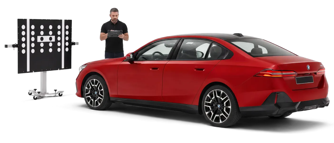 Technik kalibruje kamerę ADAS przy czerwonym sedanie